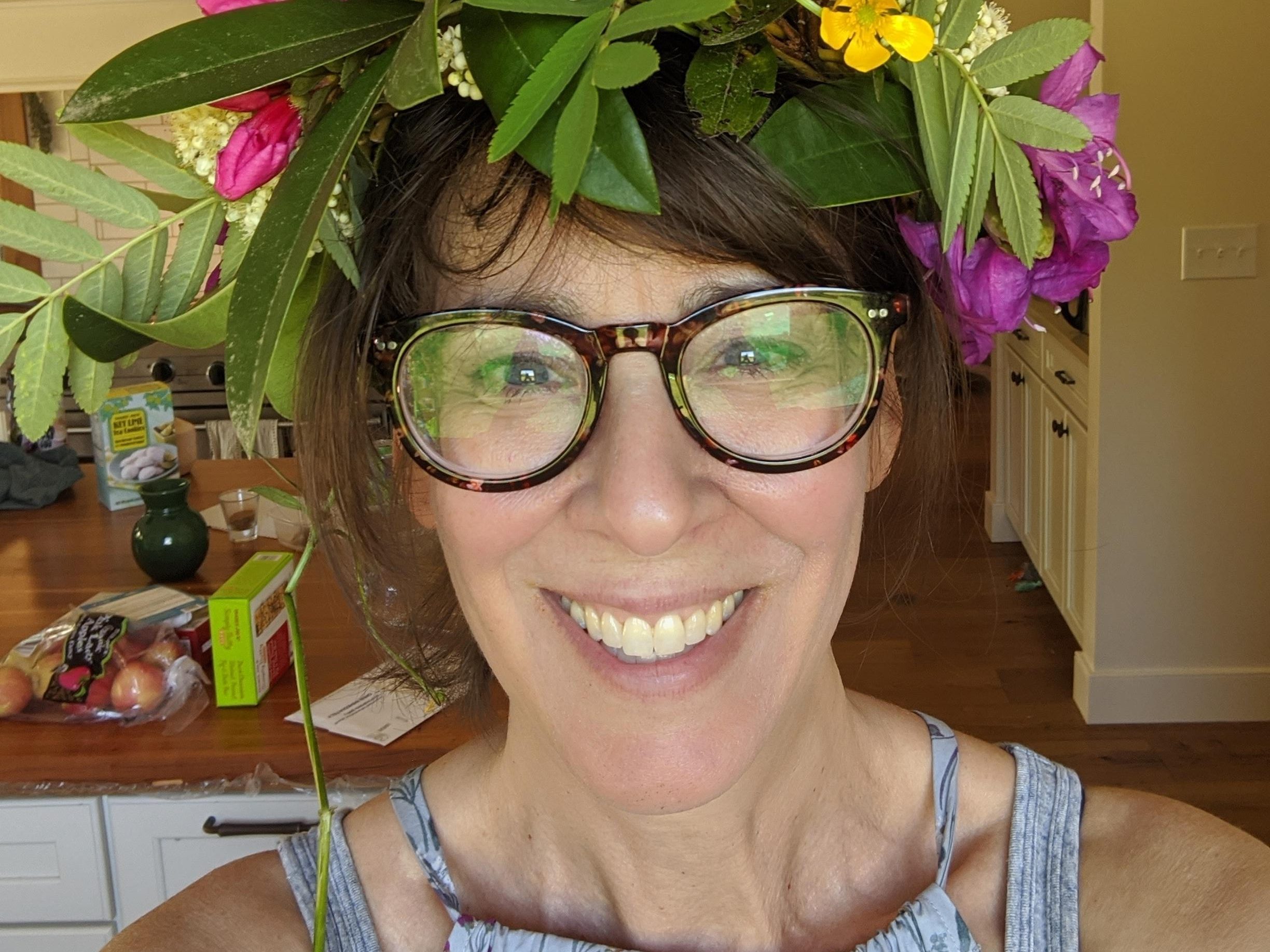White woman with glasses and a flower crown.